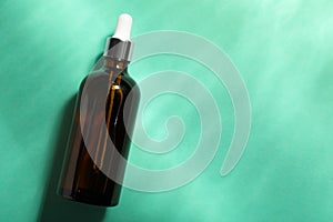 Bottle of hydrophilic oil on turquoise background, top view. Space for text