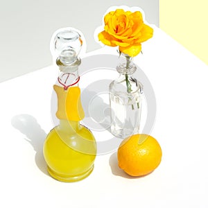 Bottle of Italian limoncello, lemon and yellow rose. Modern minimalistic still life on a geometric background with