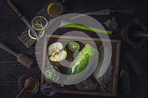 Bottle and jar with smoothie in the wooden tray with different ingredients on the wooden table