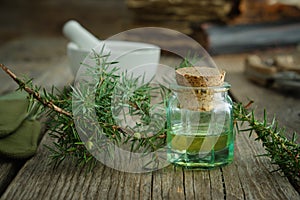 Bottle of juniper oil, mortar and Juniperus communis twigs. Herbal and homeopathic medicine