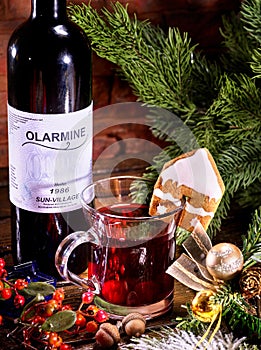 Bottle with label of red hot wine and mug .