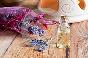 A bottle of lavender essential oil with dried lavender twigs