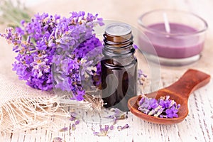 A bottle with lavender oil and delicate lavender flowers on a white background.