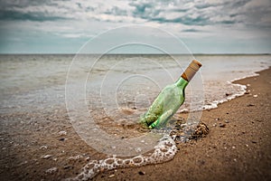 Bottle with letter on the beach sand