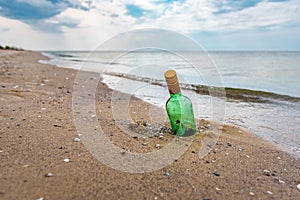 Bottle with letter stucked in the beach sand photo