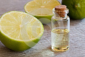 A bottle of lime essential oil with fresh limes