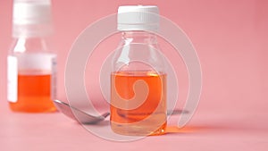 bottle with liquid medicine on pink background