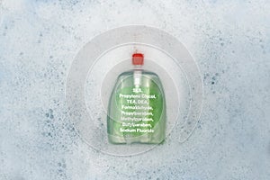 A bottle of Liquid soap floating in soapy water. Harmful composition of ingredients, detergent with SLS, Propylene Glycol, TEA, photo