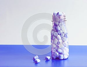 Bottle with marshmallow on blue and white background