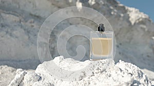 A bottle of men`s perfume with a copy space, eau de toilette on the background of a white mountain