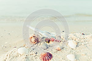 Bottle with a message or letter on the beach near seashell. SOS. Copy space.