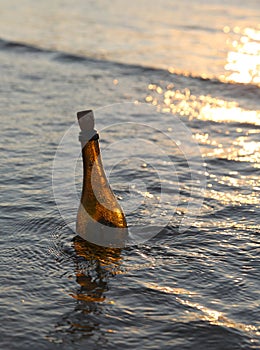 bottle with the message in the ocean at sunset i