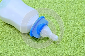 Bottle with milk for a baby on green towel