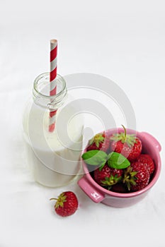 Bottle of milk and cup with strawberries