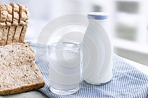 A bottle of milk and glass of milk with sliced bread on cloth indoors background for food and healthy concept