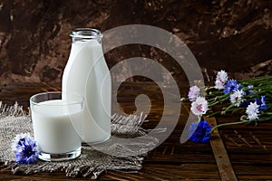 Bottle with milk and glass of milk at wooden table.