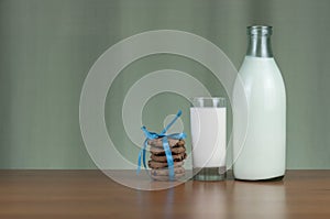 A bottle of milk and glass mug of milk with light green background