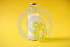 Bottle of milk and teether on color background