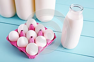 Bottle of milk and white eggs in a pink filler tray on turquoise wooden country kitchen table