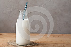 Bottle of milk on a wooden table over dark background with copy space