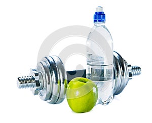 Bottle of mineral water, dumbbells and apple