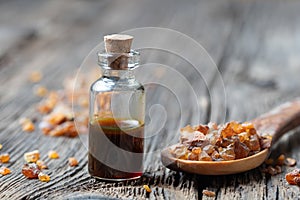 A bottle of myrrh essential oil with myrrh resin on a spoon