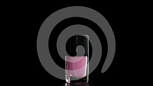 A bottle of nail polish rotates on a black background.