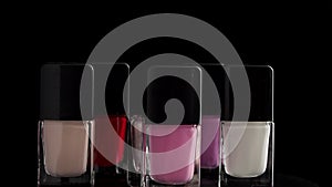 A bottle of nail polish rotates on a black background.