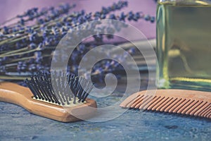 Bottle of natural cosmetic lavender oil, hair and body treatment, wooden massage brush and comb