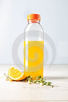 Bottle of natural orange juice with orange composing on light wooden background front view