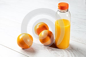 Bottle of natural orange juice with oranges on wooden table