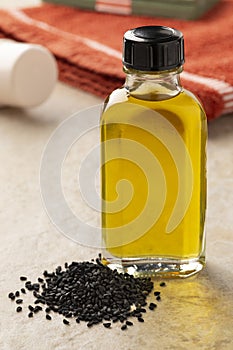 Bottle with Nigella oil and a heap of nigella seed close up