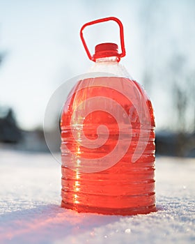 Bottle with non-freezing windshield washer fluid, snow background