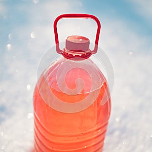 Bottle with non-freezing windshield washer fluid, snow background