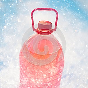 Bottle with non-freezing windshield washer fluid, snowflakes background