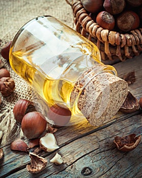 Bottle of nut oil and basket with filberts on table