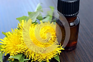 A bottle of oil on a background of yellow dandelion