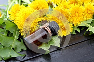A bottle of oil on a background of yellow dandelion
