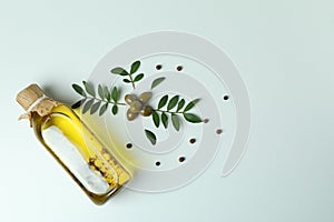 Bottle of oil, olives, twigs and pepper on white background