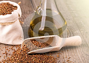Bottle of oil sesame seeds in sack on wooden table on soft sunlight