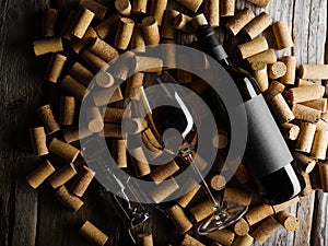 A bottle of old red wine, a glass and a corkscrew lie on wine corks. Luxury collectible wines, restaurant, hotel, advertising,