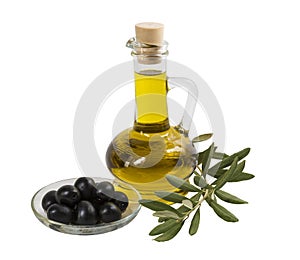 A bottle with olive oil, black olives on a plate and olive branch with leaves on a white background