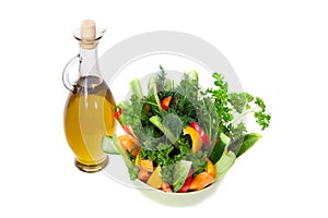 The bottle of olive oil and bowl of fresh vegetables
