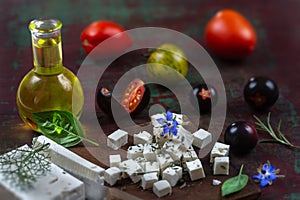 Bottle of olive oil and tomatoes with leaves feta cheese and basil isolated on a brown background