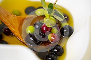 bottle of olive oil and a wooden spoon with olives