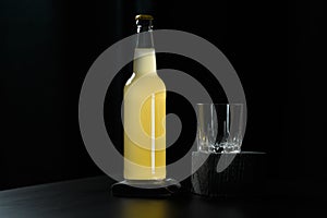 A bottle of orange juice, lemonade, alcoholic beverage and an empty glass standing on black wooden table