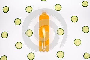 Bottle of orange smoothie on white background with cucumber pattern. Top view. Sweet drink. Detox summer drink. Healthy fresh