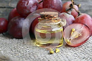 Bottle of organic grape seed oil for spa and bodycare and fresh ripe grapes berries on old wooden table.