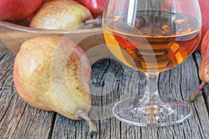 Bottle of pear aguardiente brandy and fresh pear on rustic dark