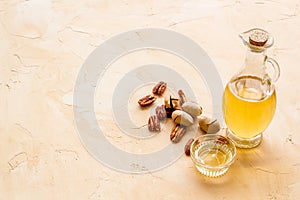Bottle of pecan oil with nuts on the table, close up